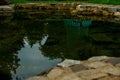 Water in the pond and reflection in the water. Stones in the foreground.