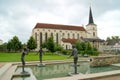 Water pool with modern open air sculptures, Church of the Exaltation of the Holy Cross in the background, Litomysl, Czechia