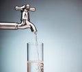 Water is poured into a glass from the tap Royalty Free Stock Photo