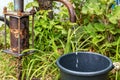 Water is poured in a thin stream from an old rusty water column in the village Royalty Free Stock Photo