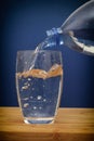 Water pouring into glass against blue background Royalty Free Stock Photo