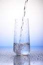 Water pouring into one-third full drinking glass Royalty Free Stock Photo