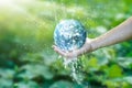 Water pouring on planet earth placed on human hand