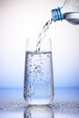 Water pouring from plastic bottle into drinking glass Royalty Free Stock Photo