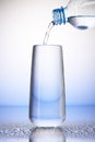 Water pouring from plastic bottle into full drinking glass Royalty Free Stock Photo