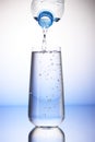 Water pouring from plastic bottle into full drinking glass Royalty Free Stock Photo