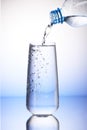 Water pouring from plastic bottle into full drinking glass Royalty Free Stock Photo