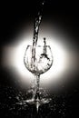 Water pouring into the wine glass on black reflective background, wine glass cup in which fresh water is poured Royalty Free Stock Photo