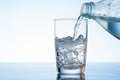 Water pours from a bottle into a glass on a clean white background