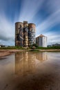 a water puddle and grain elevators with clouds in the background