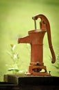 Red Old Fashioned Water Pump Against Green Background