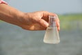 Water Purity Test. Hand holding chemical flask with liquid, lake or river in the background. Royalty Free Stock Photo