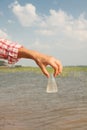 Water Purity Test. Hand holding chemical flask with liquid, lake or river in the background. Royalty Free Stock Photo