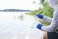 Water Purity Test. Hand in protective gloves holding a chemical flask or test tube with water. River in the background Royalty Free Stock Photo