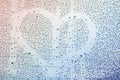 Water raindrops, romantic heart painted on the window glass. Rainbow background. Concept of love, nostalgia Royalty Free Stock Photo