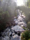 Water river with bright sun in the middle of the forest tahura curug omas waterfall stone rock