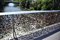 The water of the river Mura, seen through the padlocks, attached to the parapet net, on the Hauptbruecke bridge in Graz.