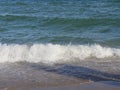 Waves roll and crash in small wavelets to the beach