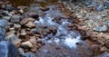 Water running down the river around rocks.