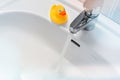 Water running from a faucet into a white sink with a rubber duck Royalty Free Stock Photo