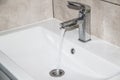 Water runs from the tap into the sink. Modern water tap in the bathroom with running flowing water in sink. Open chrome sink Royalty Free Stock Photo