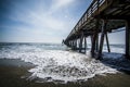 A Wave Rushes On The Sand Underneath The Imperial Beach Pier In San Diego, California