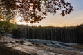 Water rushes over the edge of Yates Mill pond onto rocks in Raleigh, North Carolina at sunset in autumn Royalty Free Stock Photo