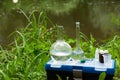 Water sampling. A set of flasks on the background of the river. Laboratory assistant takes water samples