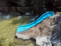 A blue water slider in pool with modeled waterfall.