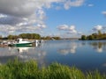 Water smooth surface of the river Kotorosl with reflecting clouds, pier with motorboats, Yaroslavl Royalty Free Stock Photo