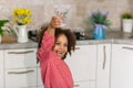 Water is the source of life. Little Black Girl is Holding a Glass of Drinking Water in the Kitchen.