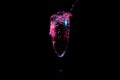 Water spilling over the edge of a glass under red and blue lights isolated on a black background Royalty Free Stock Photo