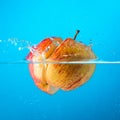 Water splash. Apple under water. Blue background. Royalty Free Stock Photo