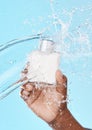 Water splash, black man and hand with skincare bottle in studio on a blue background. Hygiene, cleaning and male model