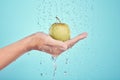 Water splash, cleaning and hands with apple in studio isolated on a blue background. Nutritionist, fruits and model or Royalty Free Stock Photo