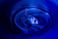 Water splash in dark blue color with a drop of water flying from Royalty Free Stock Photo