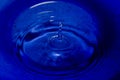 Water splash in dark blue color with a drop of water flying from Royalty Free Stock Photo