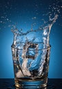 Water Splash in Glass with Ice Cubes on Blue Background Royalty Free Stock Photo