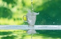 Water splash in glass Select focus blurred background.Drink water pouring in to glass over sunlight and natural green Royalty Free Stock Photo