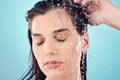 Water splash, hair care and face of woman in shower in studio isolated on a blue background. Beauty, eyes closed and Royalty Free Stock Photo