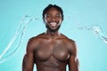 Water splash, portrait and black man isolated on blue background for face cleaning, body shower and skincare. Strong Royalty Free Stock Photo