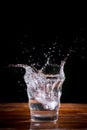 Water splash with transparent glass on wooden table with black background. Copy space for your text Royalty Free Stock Photo