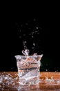 Water splash with transparent glass on wooden table with black background. Copy space for your text Royalty Free Stock Photo