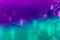 Water splashed on the blurred violet turquoise blue glossy background