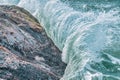 Water splashes close up. Crystal clear sea water beats against the rocks. Sea waves break on the stone shore of the ocean, blue