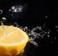 Water splashing over half a lemon. Black background. Royalty Free Stock Photo