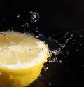 Water splashing over half a lemon. Black background. Royalty Free Stock Photo