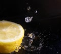 Water splashing over half a lemon. Black background. Royalty Free Stock Photo