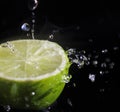 Water splashing over half a lime. Black background.