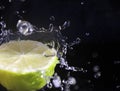 Water splashing over half a lime. Black background.